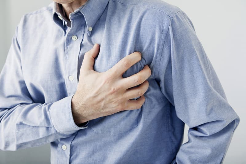A male clutching his chest in pain due to suffering from a heart attack (cardiac arrest)
