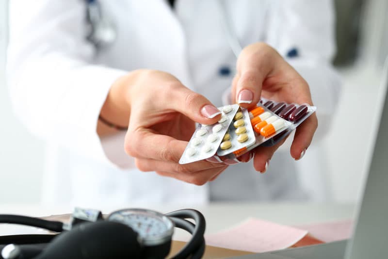 A pharmacist holding various blister packs of painkiller medications