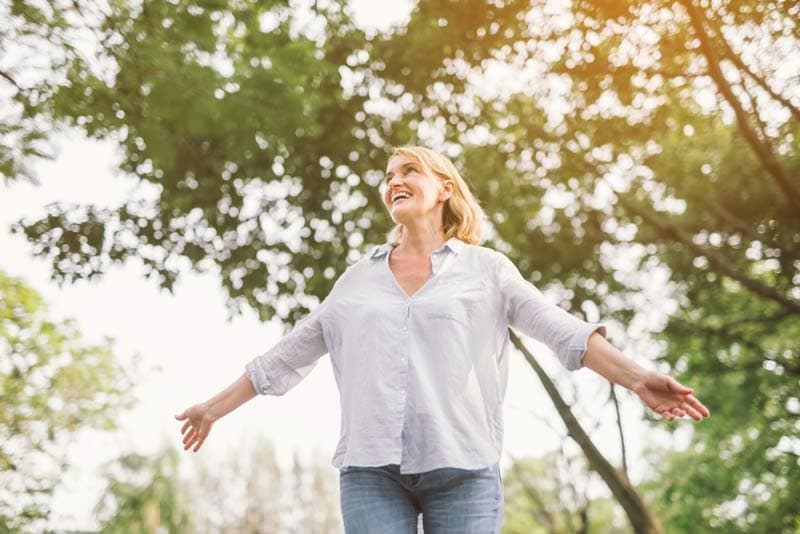 A lady looking happy whilst walking in the park