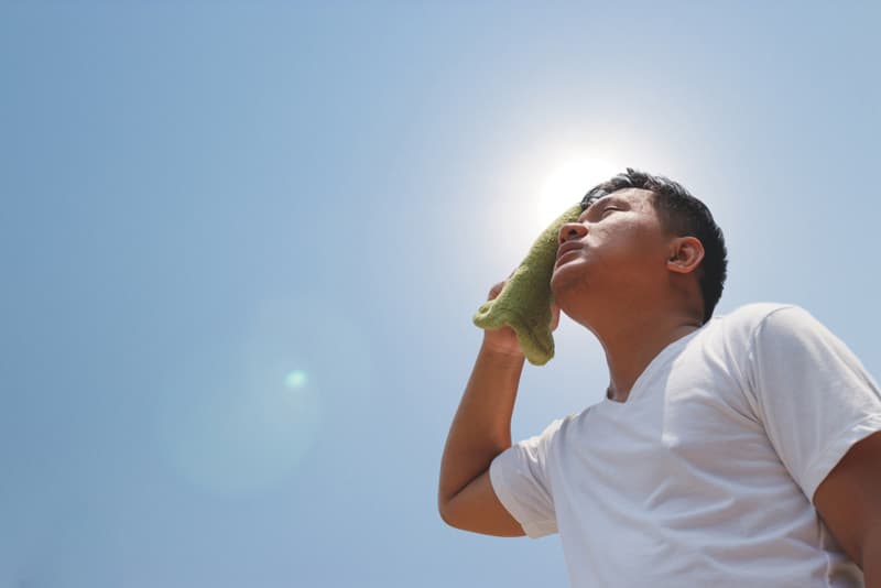A man wiping his head on a hot day