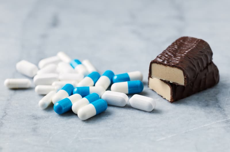 Arginine supplements  next to a chocolate bar