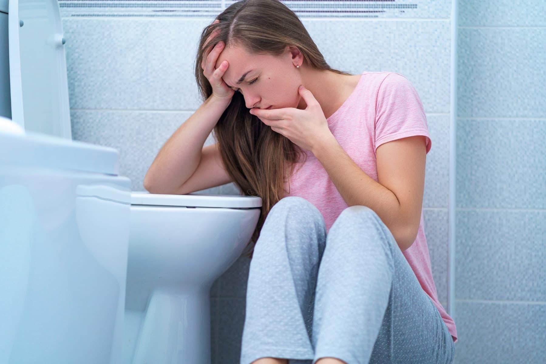 A lady sat at the toilet feeling nauseous