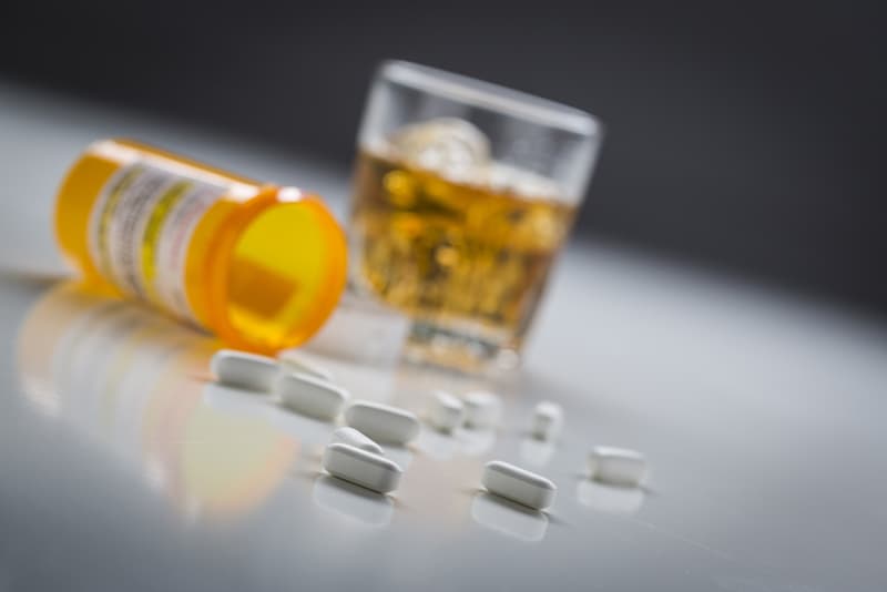 Co-codamol tablets and a glass of alcohol next to each other