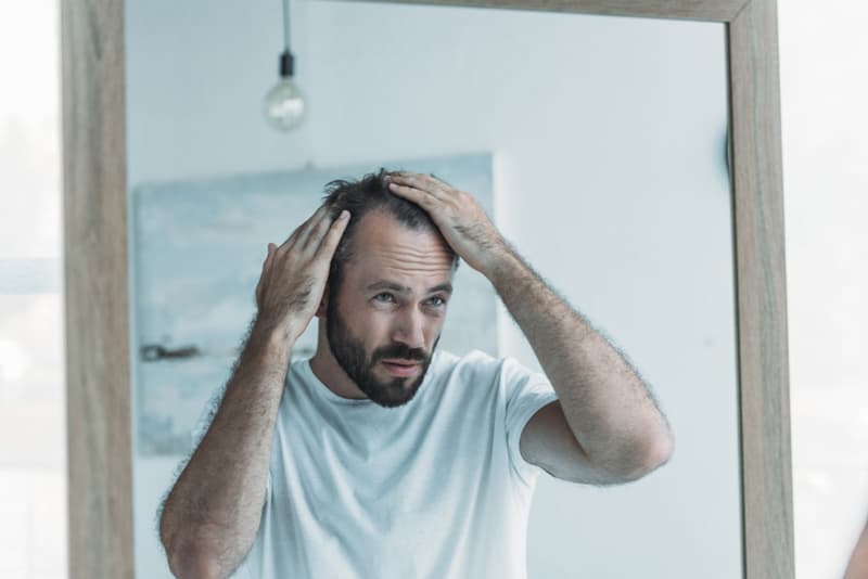 A man looking into the mirror at his receding hairline