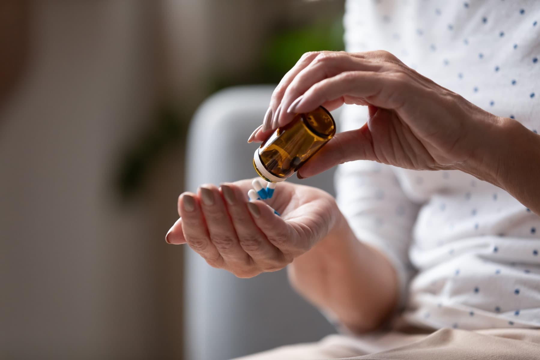 A hand pouring a jar of propranolol tablets into a hand