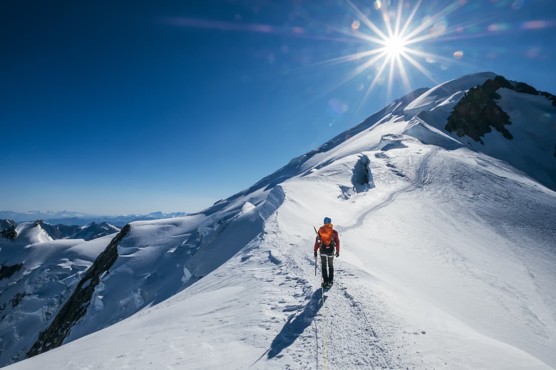A man climbing to the top of a snowy mountain