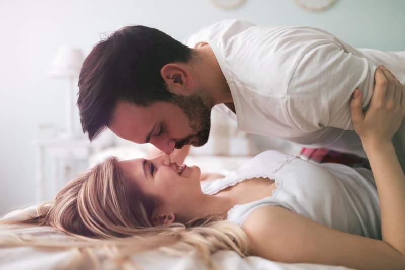 A man and a woman kissing on a bed