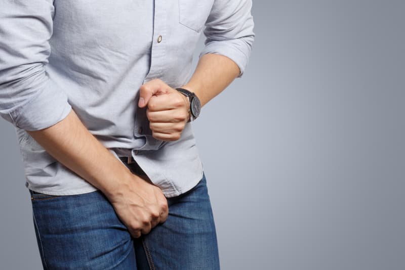 A man covering his crotch area