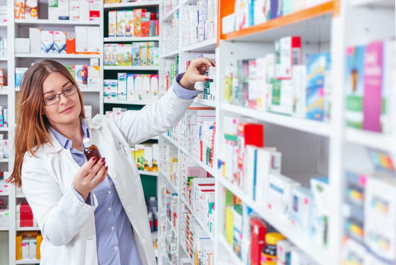 A pharmacist looking for medication on a shelf in a pharmacy