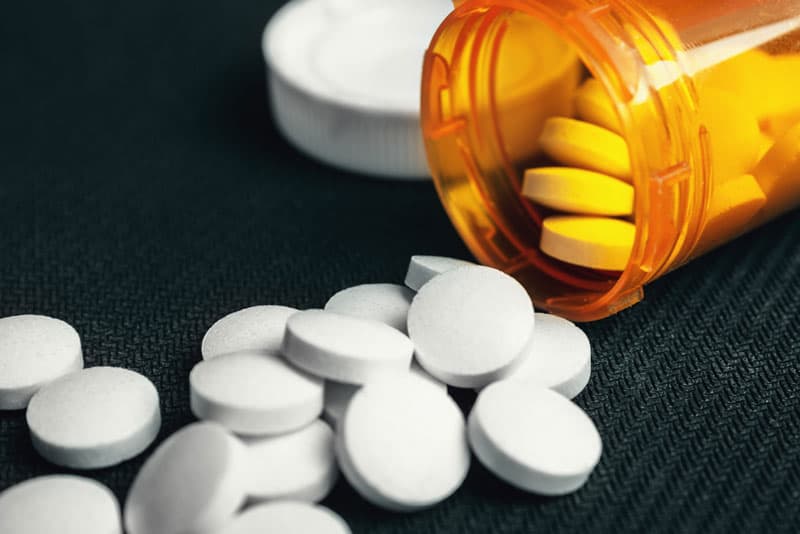 Painkiller tablets spilling out of a pill box