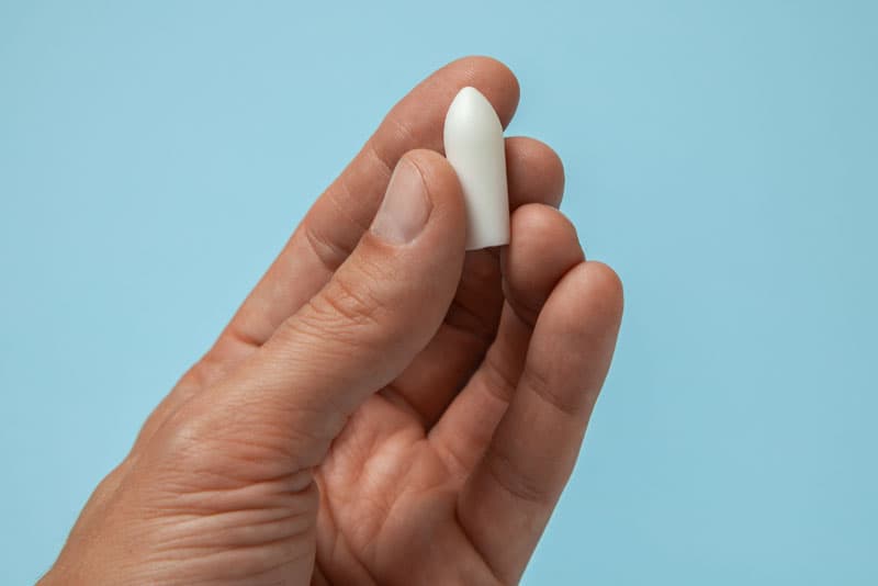 A hand holding a medical tablet for the treatment of thrush