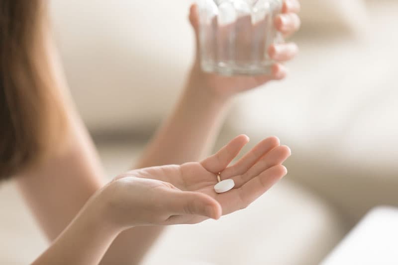 A lady holding a painkiller tablet