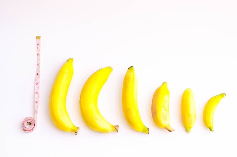 A tape measure rolled out on the side of 6 bananas