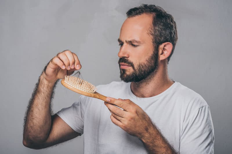 A man pulling loose hair from his hair comb