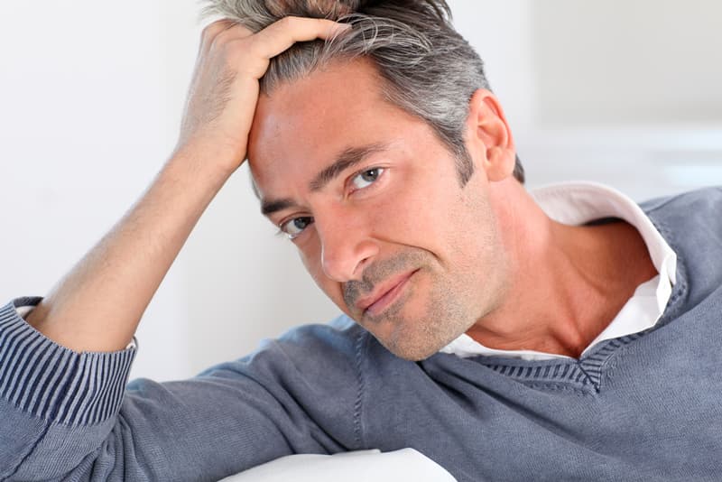 A middle aged man looking happy running his hand through his full head of hair