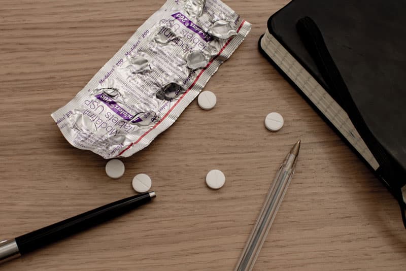 A blister pack of Modafinil pills which has been opened and the pills spread across the table