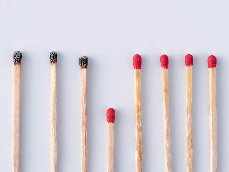 A row of separate match sticks with a shorter match stick in the centre of them all