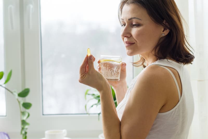 A lady taking a supplement with a glass of water