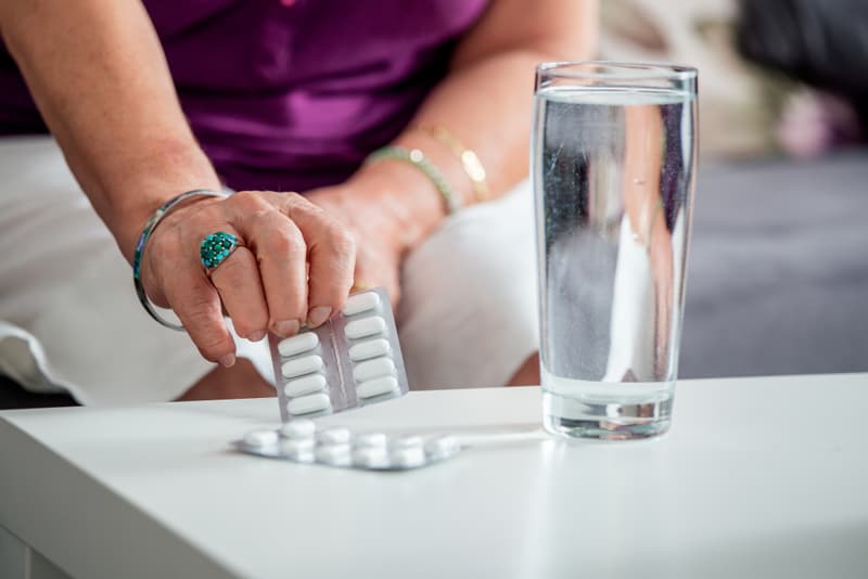 A hand reaching out for a blister pack of supplement tablets