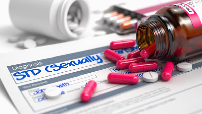 A jar of pills spilled out on a prescription for a sexually transmitted disease