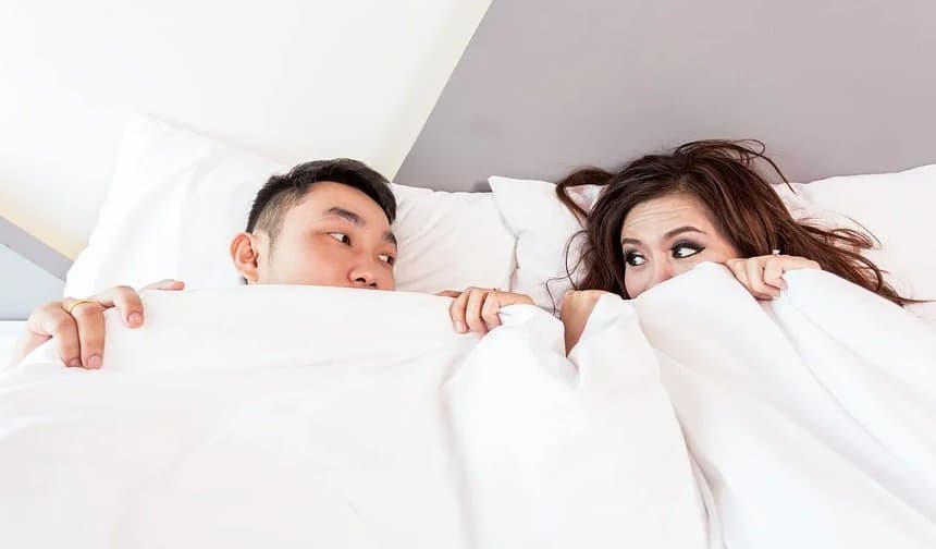 A man and a woman under the cover staring at each other