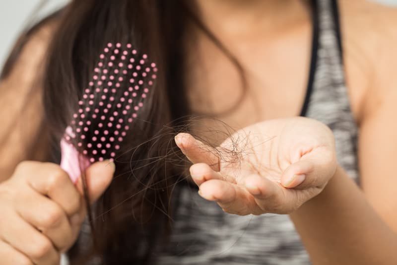 A lady holding loose hairs in the hand after combing her head