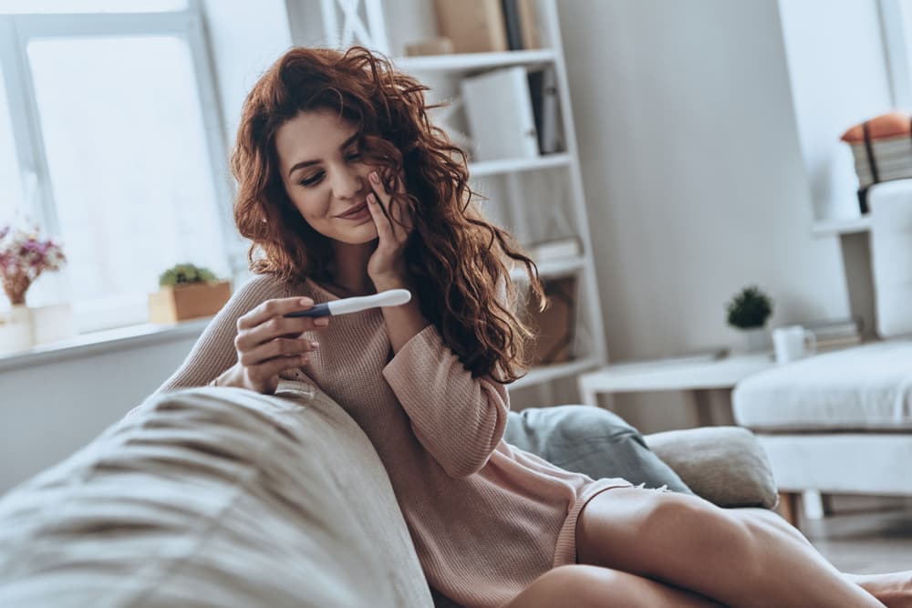 A lady looking at a positive pregnancy test