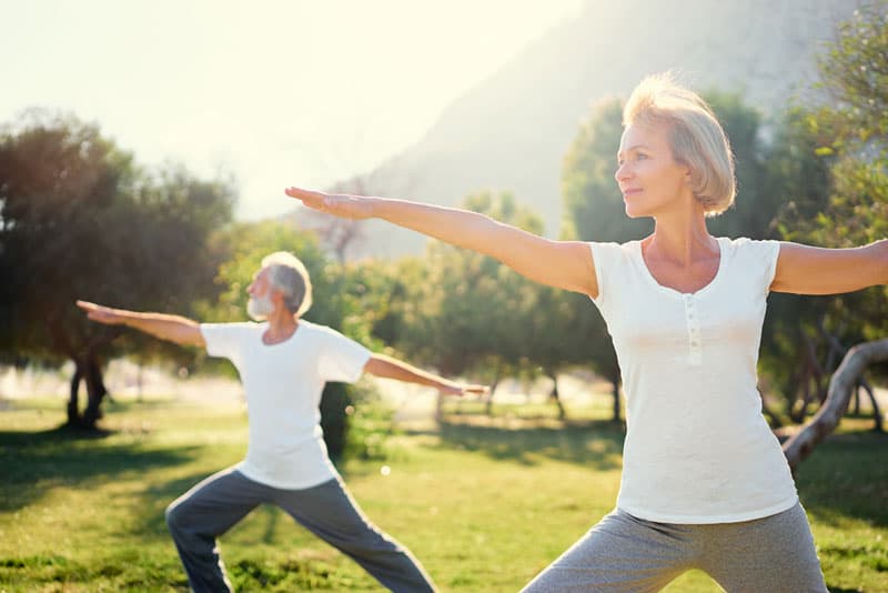 A man and woman doing yoga in the park