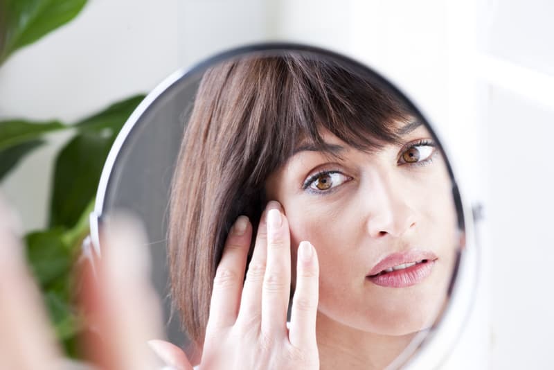 A lady looking into the mirror and assessing her hair
