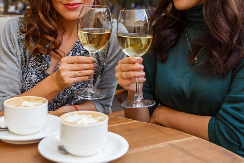 Two women drinking wine and coffee at a restaurant
