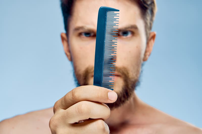 A man holding up a hair comb
