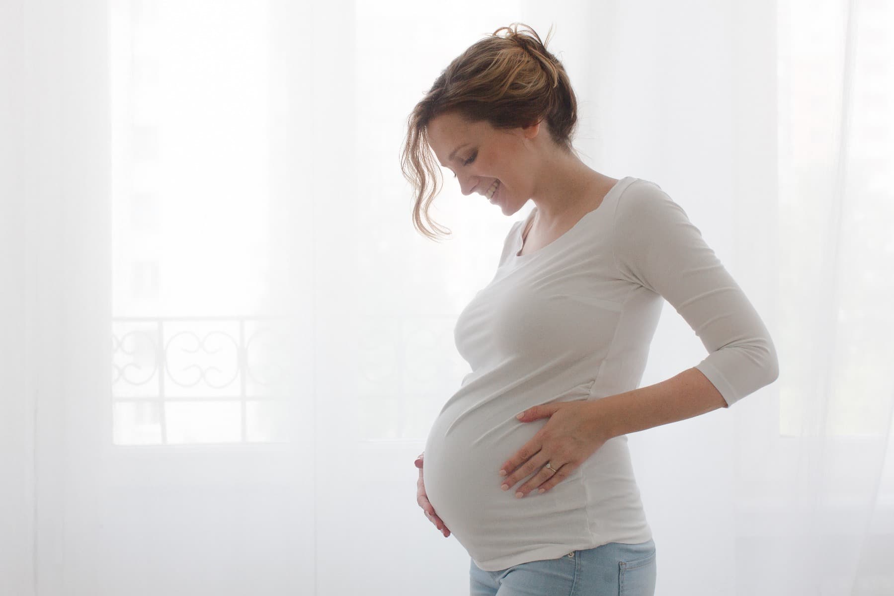 A pregnant lady smiling at her baby bump