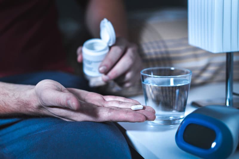 A hand holding a Zopiclone tablet