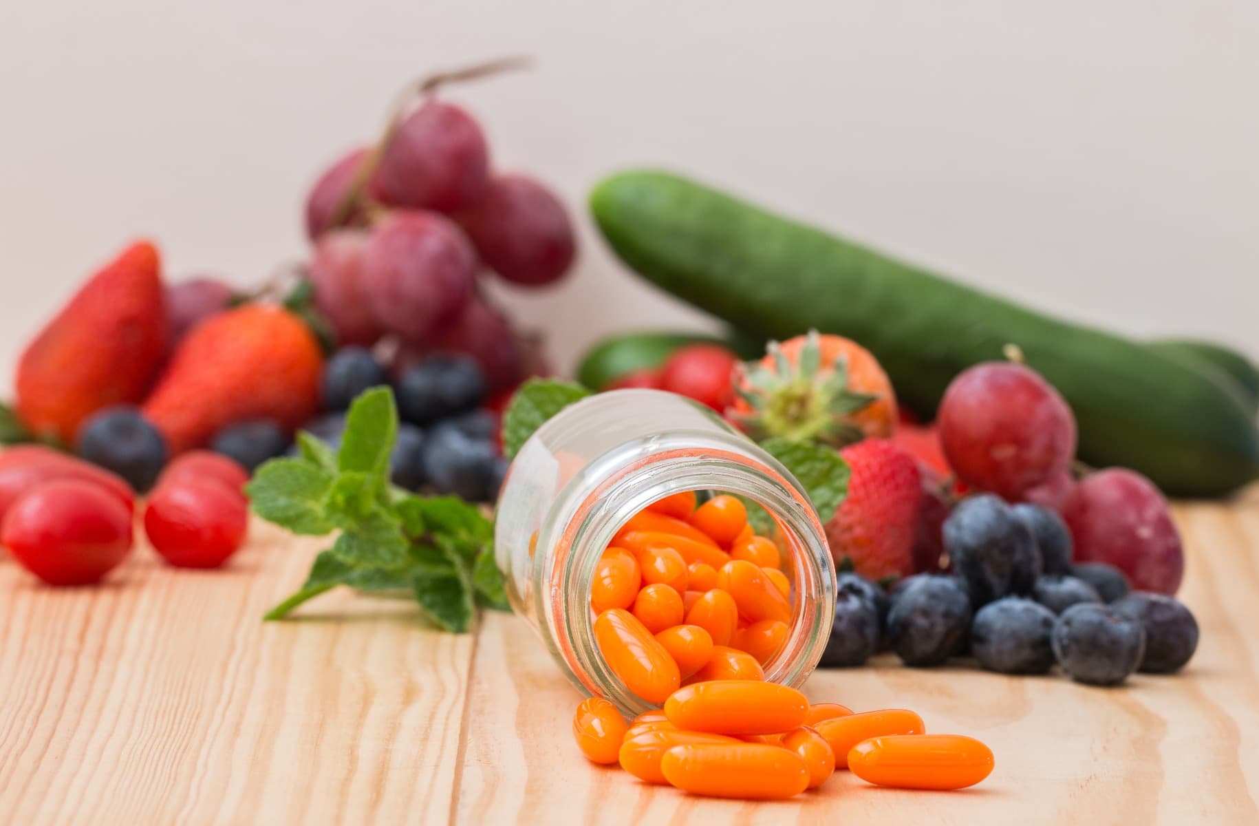 A mixture of fruit and vegetables behind a jar of CoQ10 supplements