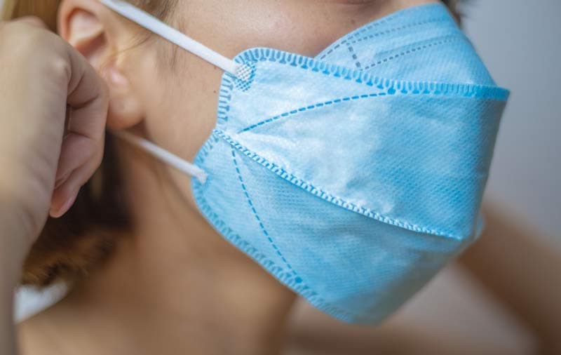 A lady putting on a protective face mask