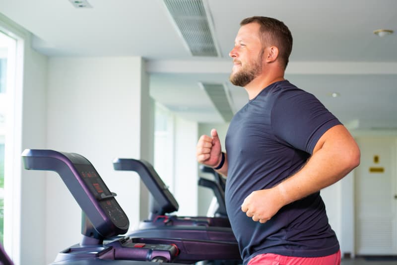 An overweight man running on a treadmill