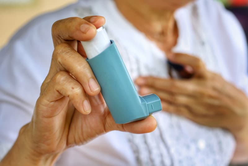 A salbutamol inhaler being held in an elderly lady's hand