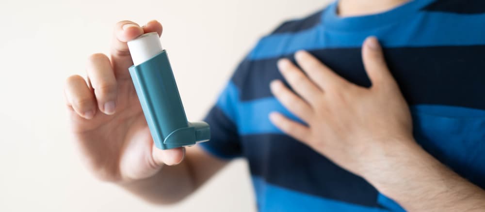 A hand holding up a Ventolin (salbutamol) inhaler