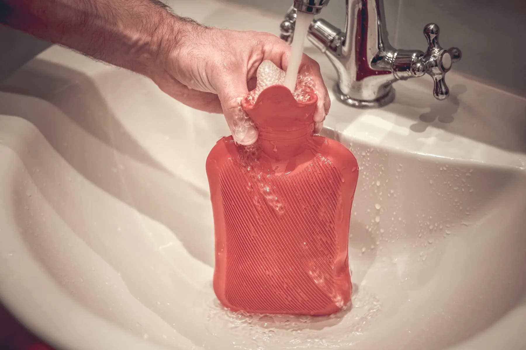 A hot water bottle being filled up in the sink