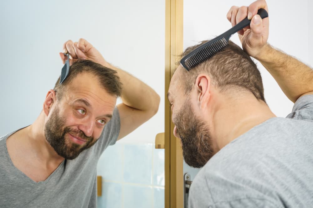 A man combing his hair whilst looking in the mirror