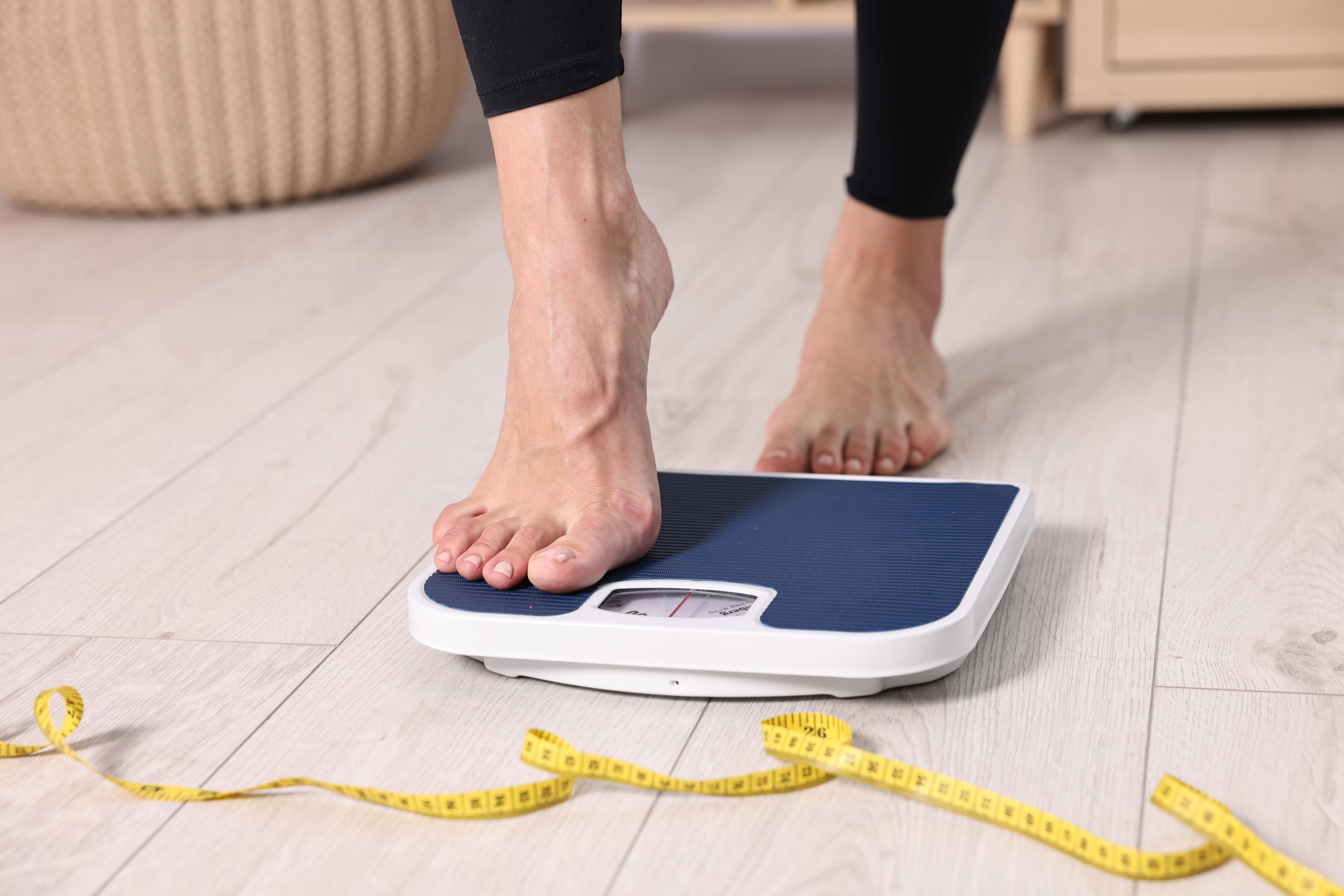A pair of legs stepping on weighing scales