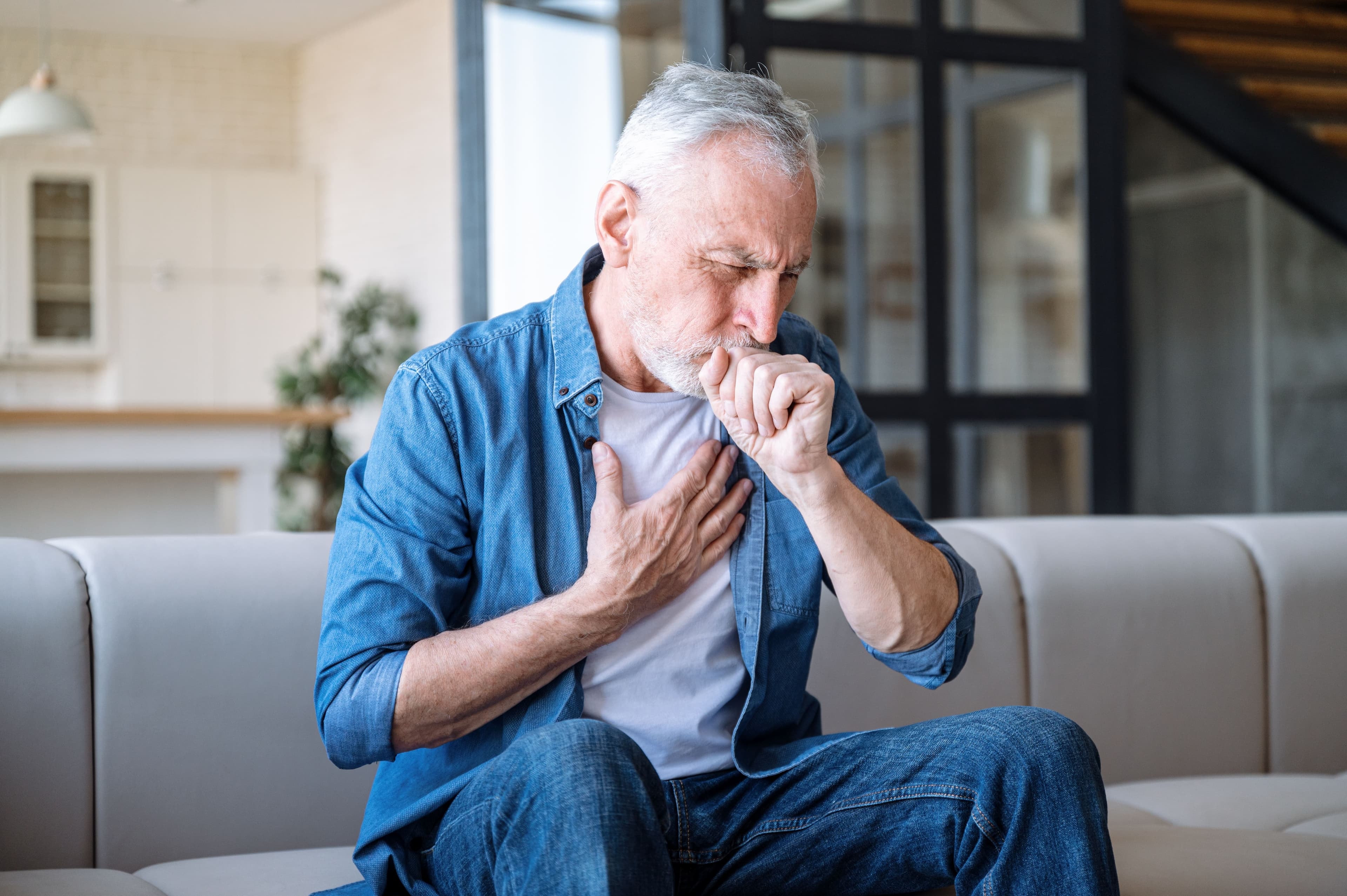 An old man sat down whilst coughing