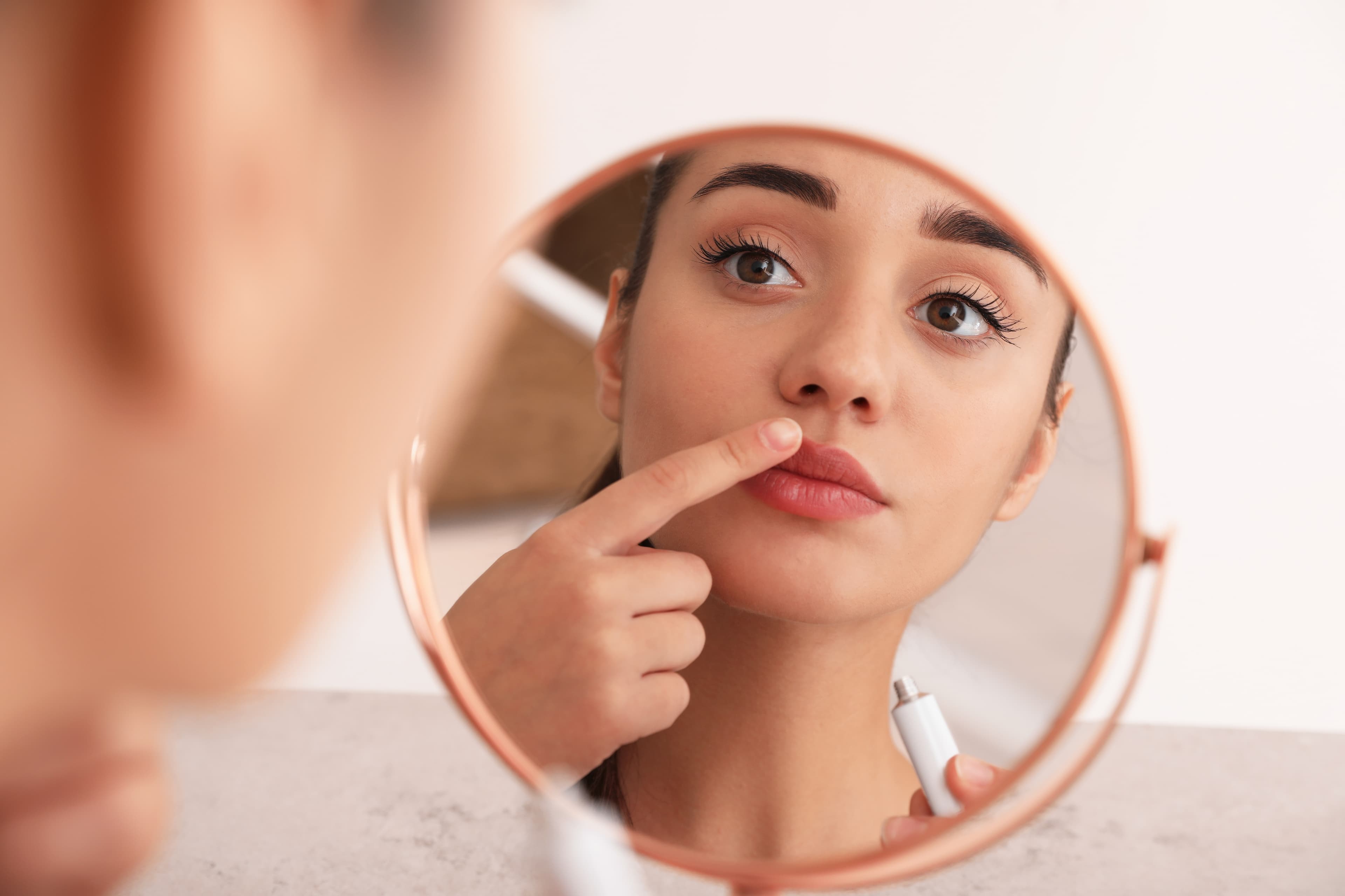 A lady assessing her  face for herpes