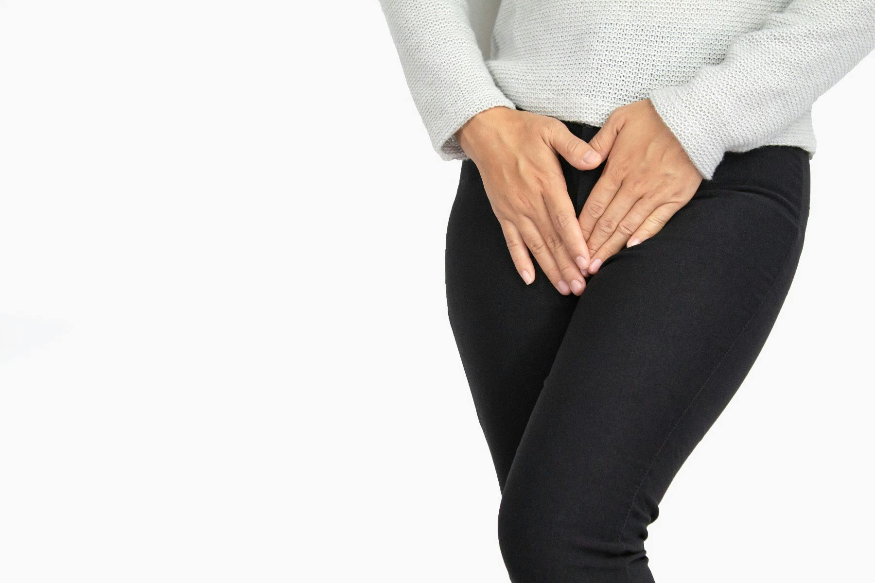 A woman covering her groin with her hands.