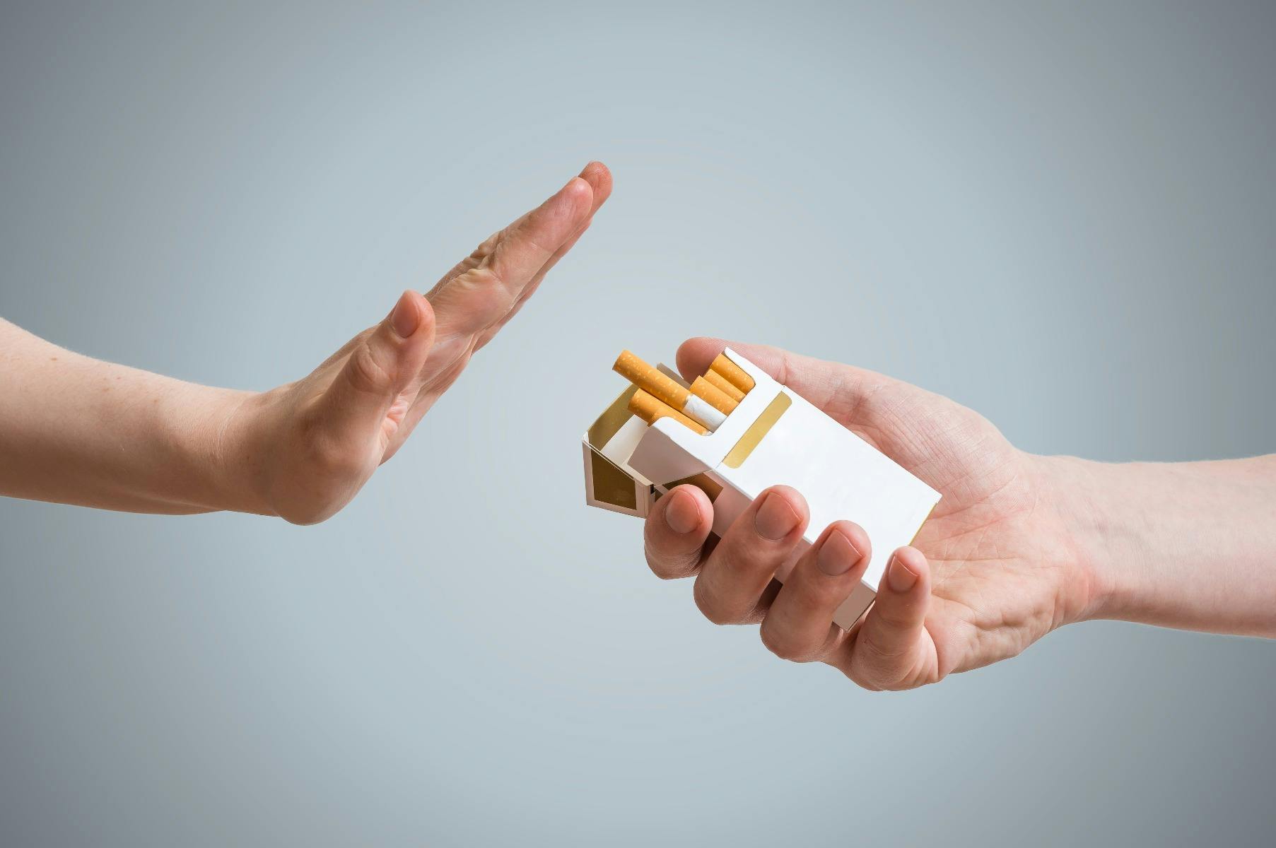 A hand rejecting a packet of cigarettes.
