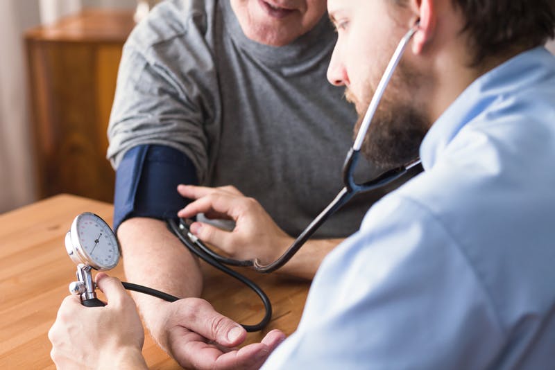 doctor using blood pressure monitor on a patient to assess their blood pressure levels