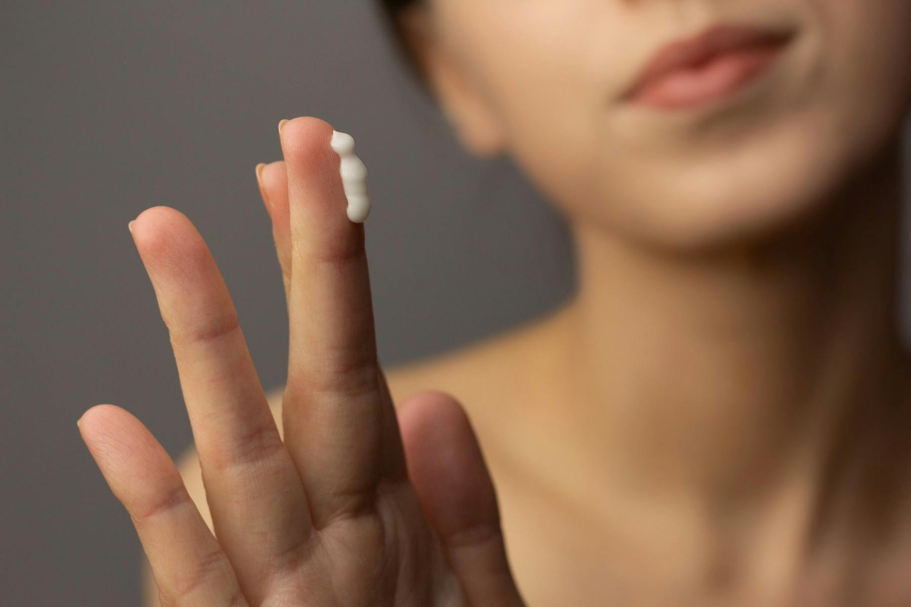 Lady applying Tretinoin cream to her fingertip to add it to her acne