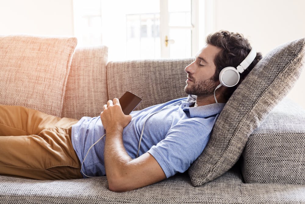 Man taking a nap on his sofa going to sleep after listening to the songs for sleep playlist on Spotify