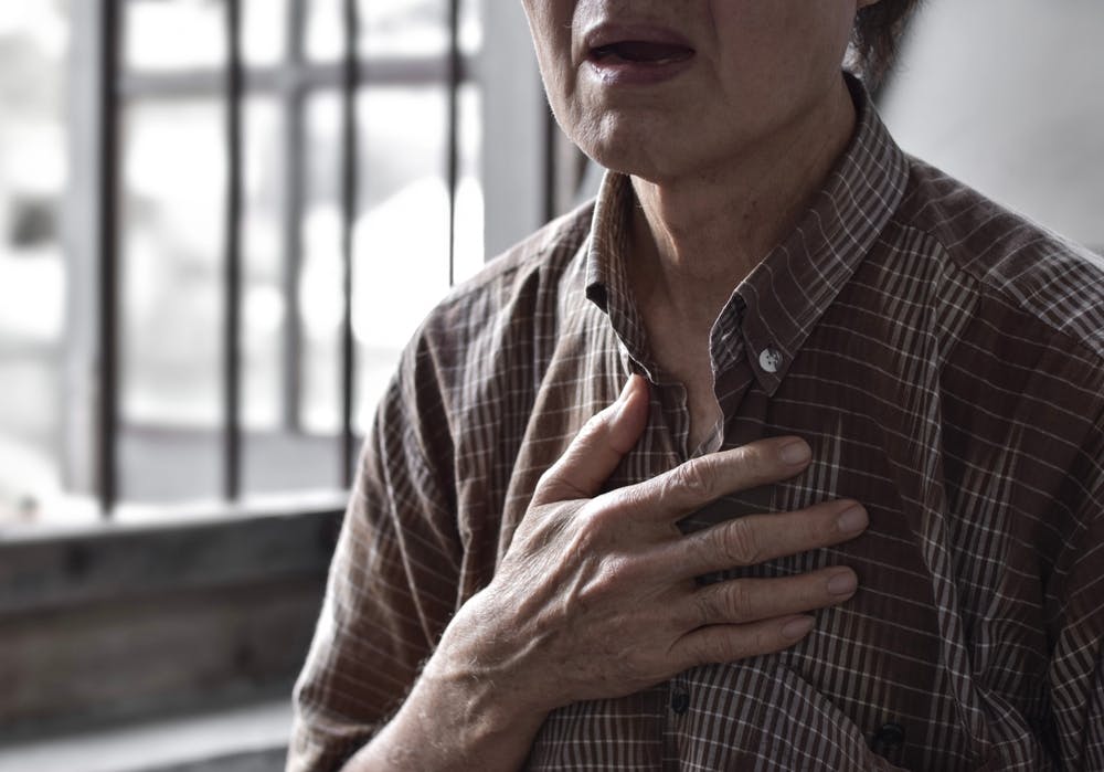 Old lady clutching her chest as she struggles to breathe