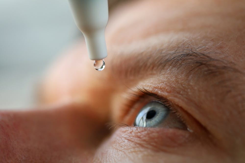 Man applying Opticrom Aqueous eye drops to his eyes